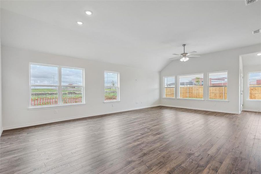 Unfurnished living room featuring vaulted ceiling, dark hardwood / wood-style flooring, and ceiling fan