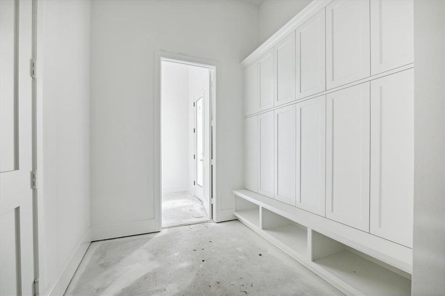 A view of the oversized mudroom inside the garage pedestrian door to the left of the picture.  Functional and stylish with full lockers to hide away all the things found in a mudroom.  First floor powder room or future pool bath located through the door shown at back of this picture.  Photo as of 9/3/2024