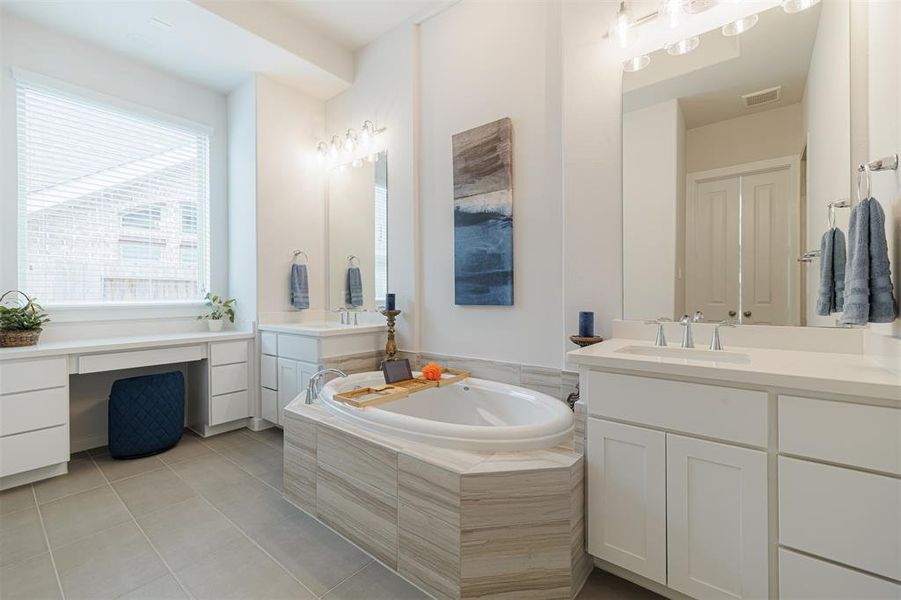 Spa-like primary bath with his and hers sinks, vanity area and a soaking tub.