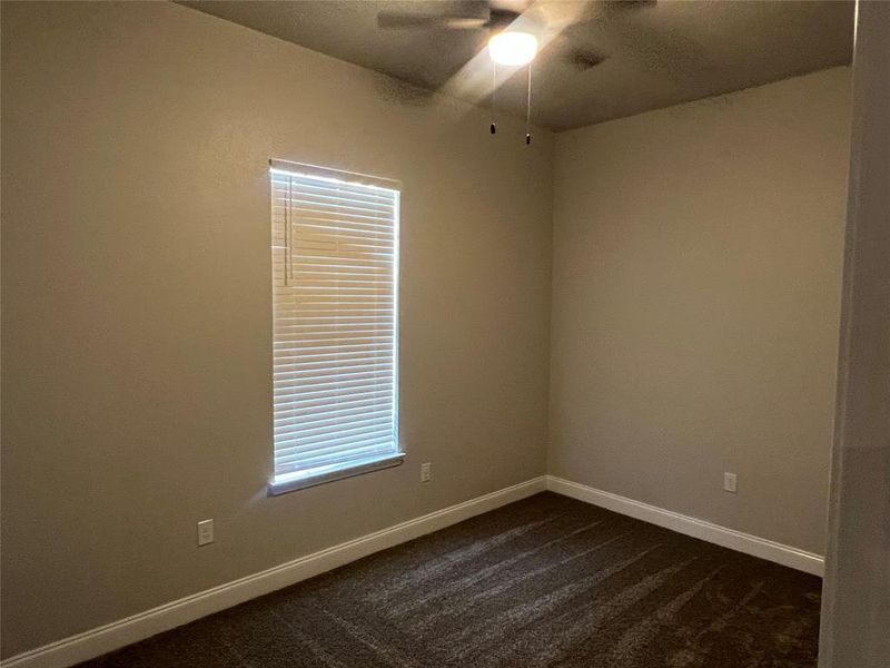 Spare room featuring dark colored carpet and ceiling fan