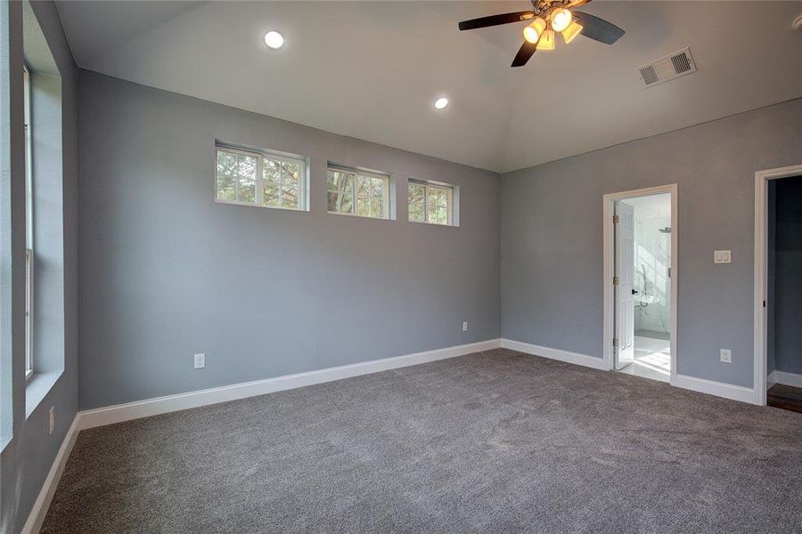 Master bedroom with vaulted ceiling, ceiling fan, canned lights and carpet flooring