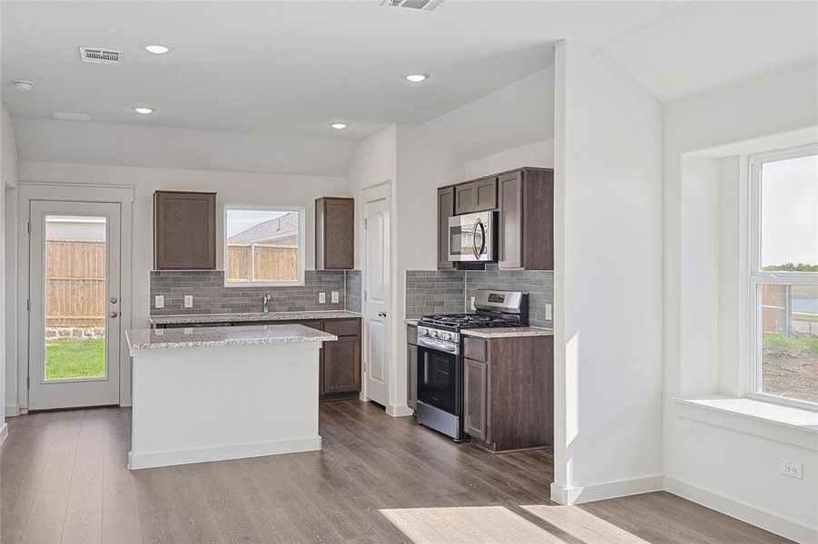 Kitchen with lofted ceiling, appliances with stainless steel finishes, light hardwood / wood-style floors, and plenty of natural light