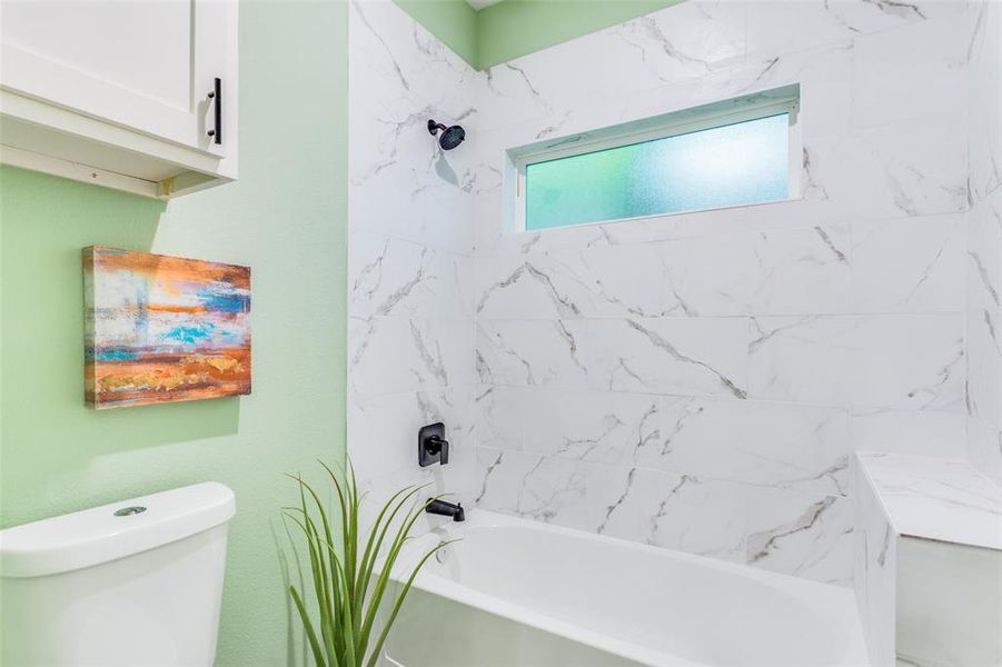 Bathroom featuring tiled shower / bath combo and toilet