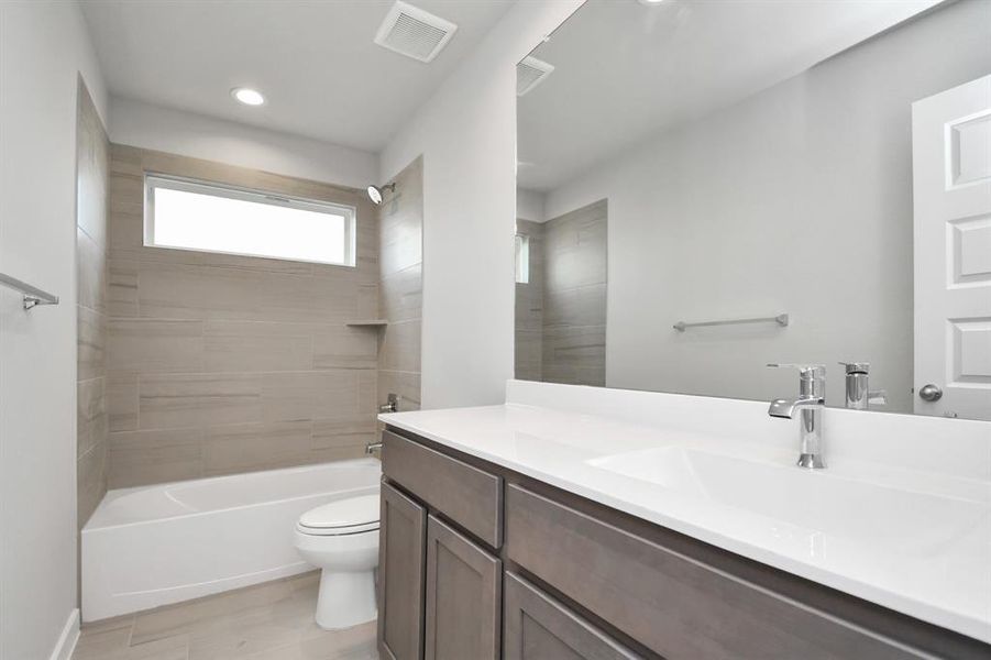 Experience sophistication in the secondary bathroom, where tile flooring complements a bath/shower combo with tile surround. Light wood cabinets complete with a beautiful light countertop, enhances the space for a truly inviting ambiance.