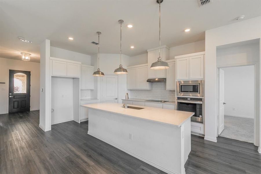 Kitchen featuring an island with sink, appliances with stainless steel finishes, sink, and white cabinetry