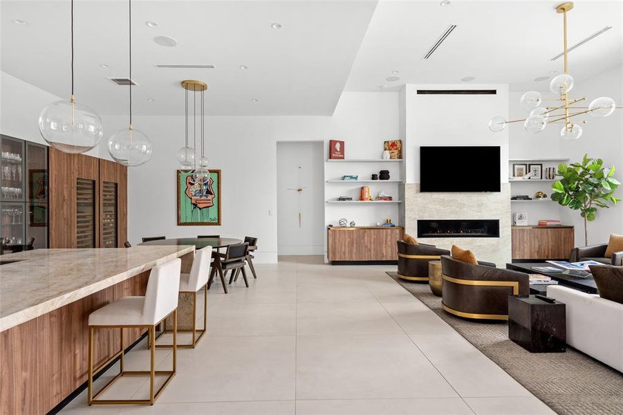 This inviting family room, part of a seamless open-concept design, connects effortlessly with the kitchen and dining areas. Custom built-in shelving flanks the contemporary fireplace completing the clean aesthetic of the space.