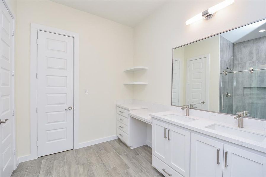 Beautiful en suite bathroom with marble countertops, white cabinetry, double sink and a luxurious sit-down vanity area.