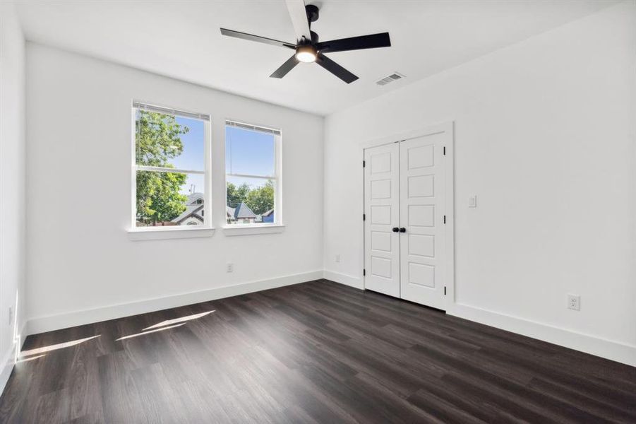 Unfurnished bedroom featuring ceiling fan, a closet, and dark wood-type flooring