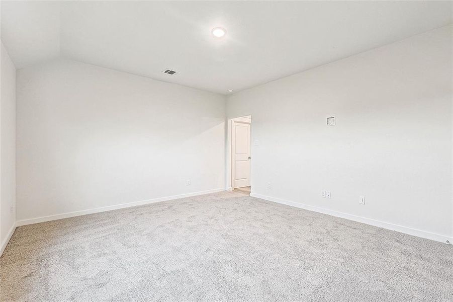 Carpeted empty room featuring lofted ceiling