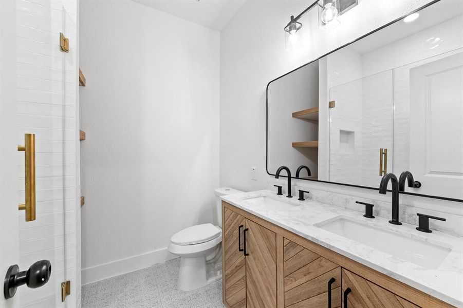 Second primary bath with double sinks and frameless glass walk in shower.