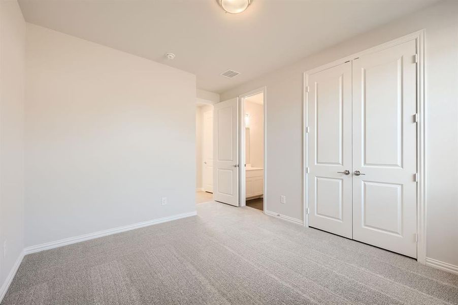 Unfurnished bedroom featuring a closet, light carpet, and ensuite bathroom