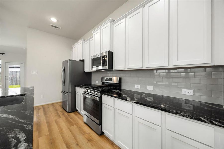 This stunning kitchen displays such a beautiful contrast with light cabinets, custom neutral paint, dark granite countertops, modern backsplash, SS appliances, oversized kitchen island with extra storage, breakfast bar, recessed lighting, high ceilings and walk in pantry.