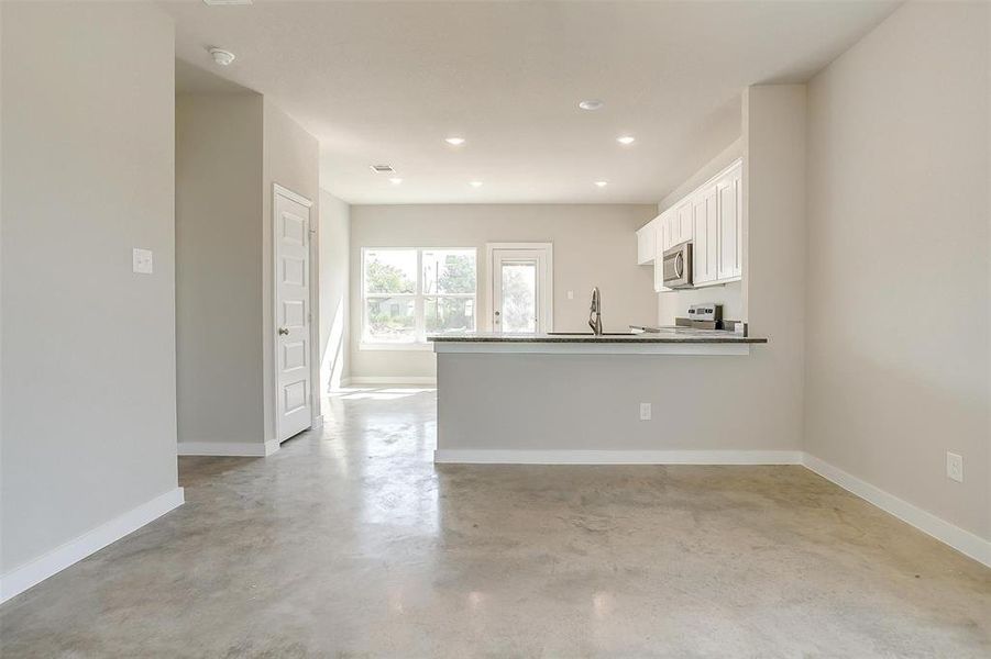 Kitchen featuring white cabinets, sink, stove, and kitchen peninsula