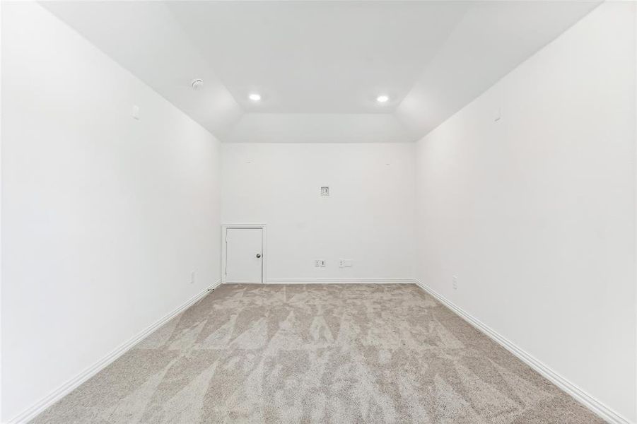 Empty room with lofted ceiling and light colored carpet