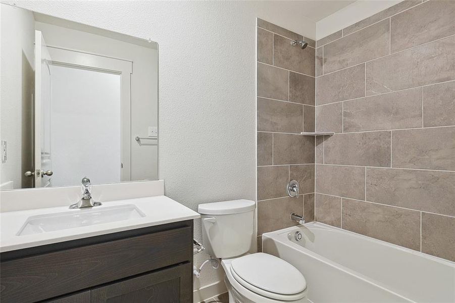 Full bathroom featuring vanity, toilet, and tiled shower / bath combo