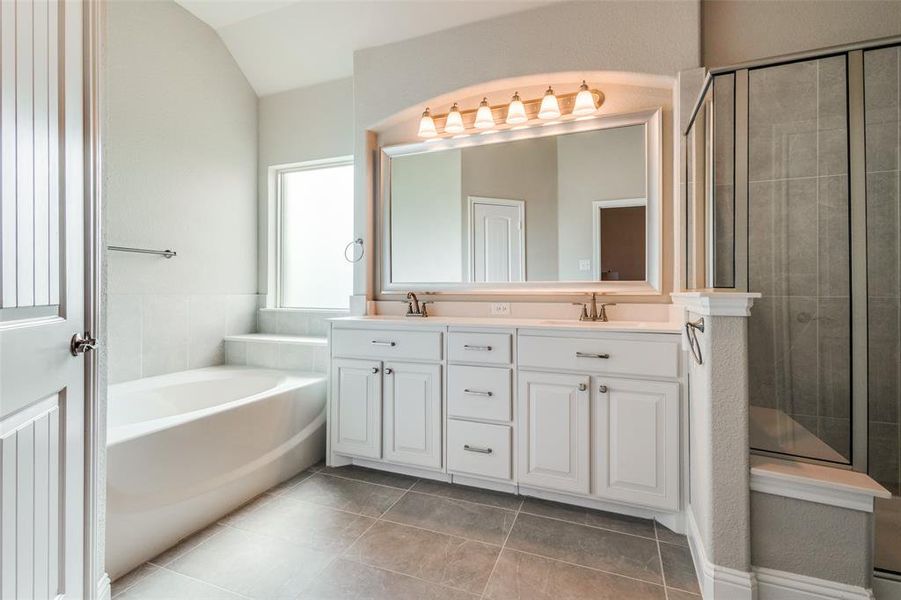 Bathroom with independent shower and bath, tile patterned flooring, vaulted ceiling, and double sink vanity