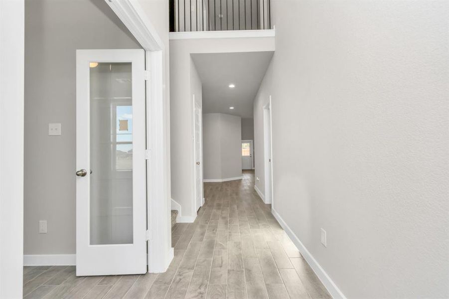 The majestic entryway allures with its high ceilings, embellished with sophisticated wood-look tile flooring and sleek oversized baseboards. Sample photo of completed home with similar floor plan. As built color and selections may vary.