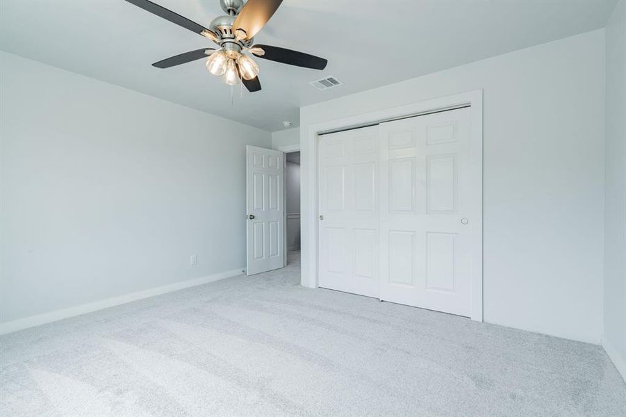 Unfurnished bedroom featuring a closet, ceiling fan, and light colored carpet