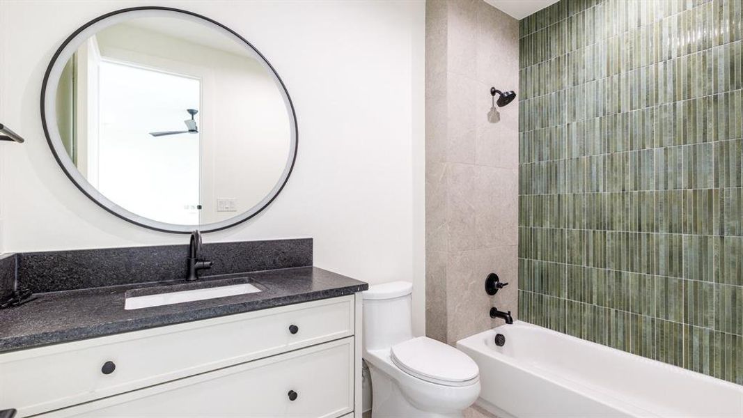 Full bathroom with tiled shower / bath combo, toilet, and vanity