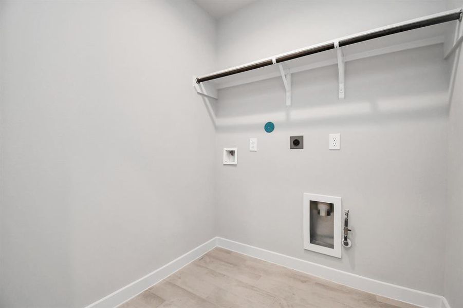 Located on first floor, a stylish laundry room where practicality meets a contemporary aesthetic. The dark finishes lend a sophisticated touch, creating a space that is both functional and visually appealing. Both electric and gas connections available. Sample photo of completed home with similar floor plan. Actual colors and selections may vary.