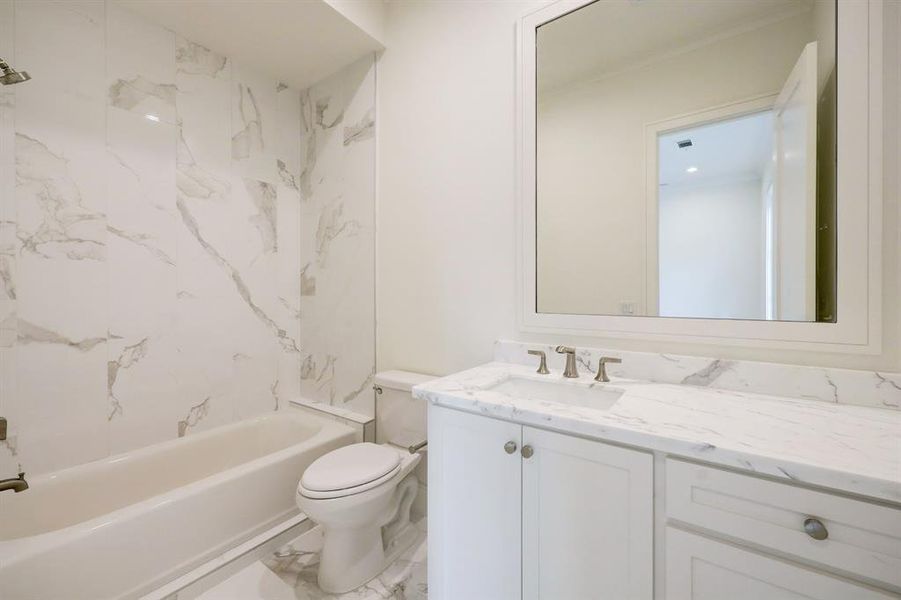 The secondary bedroom's ensuite bath with gorgeous tub/shower combination with stone to the ceiling, marble floor and countertop. We love the framed mirror! Such a nice touch!