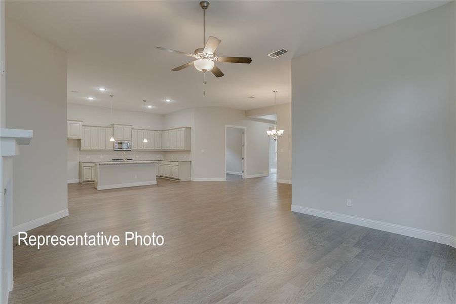 Unfurnished living room featuring light hardwood / wood-style flooring and ceiling fan with notable chandelier