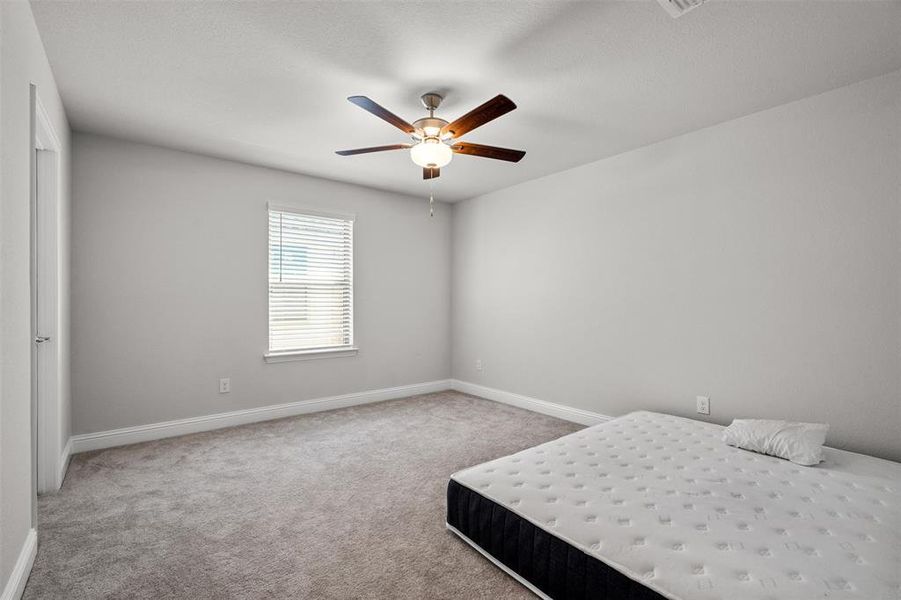 Unfurnished bedroom featuring ceiling fan and carpet floors