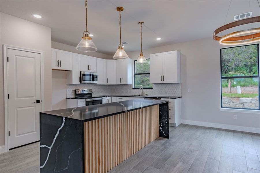 Kitchen with stainless steel appliances, white cabinetry, a center island, and backsplash