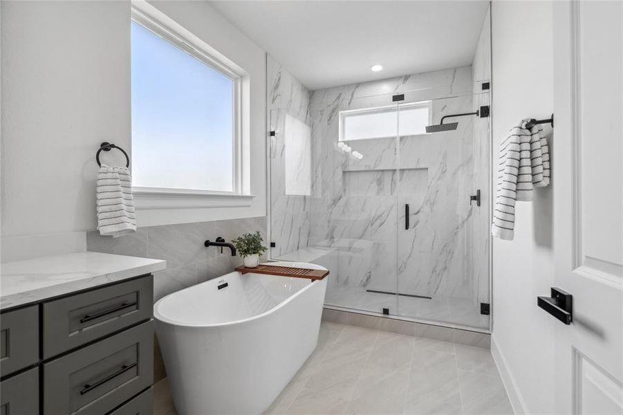 Enjoy a beautifully designed frameless walk-in shower with sleek, modern fixtures and a standalone tub for ultimate relaxation. This spacious retreat blends elegance and comfort, offering a luxurious bathing experience.