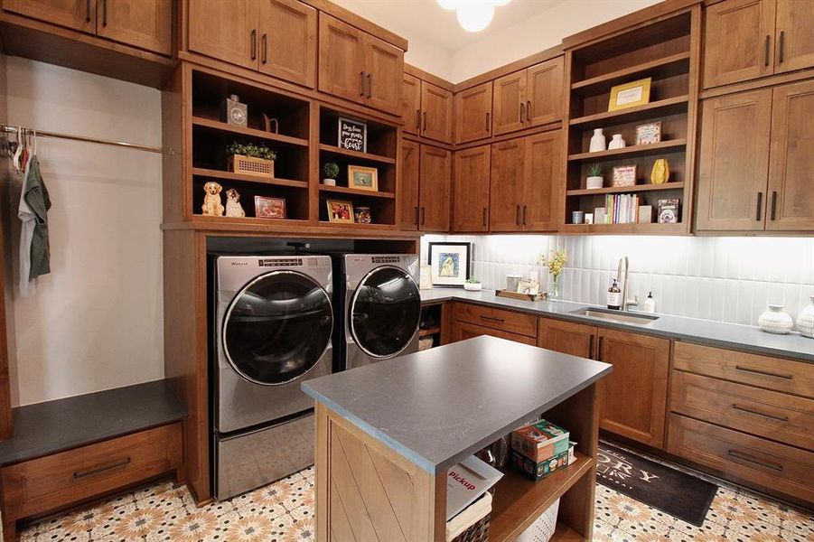 This massive laundry room offers a center island, ample storage space, and a sink.