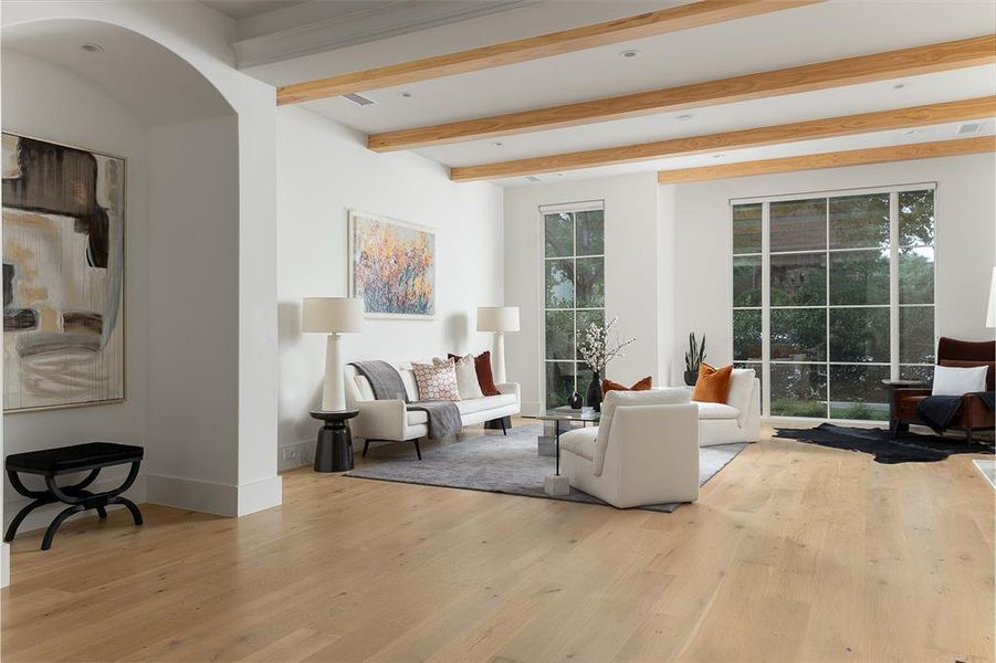 Living room with beamed ceiling, light hardwood / wood-style floors, and a wealth of natural light