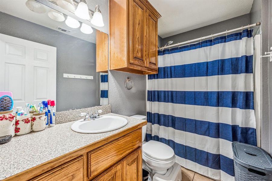 Bathroom with tile patterned floors, vanity, toilet, and a shower with shower curtain