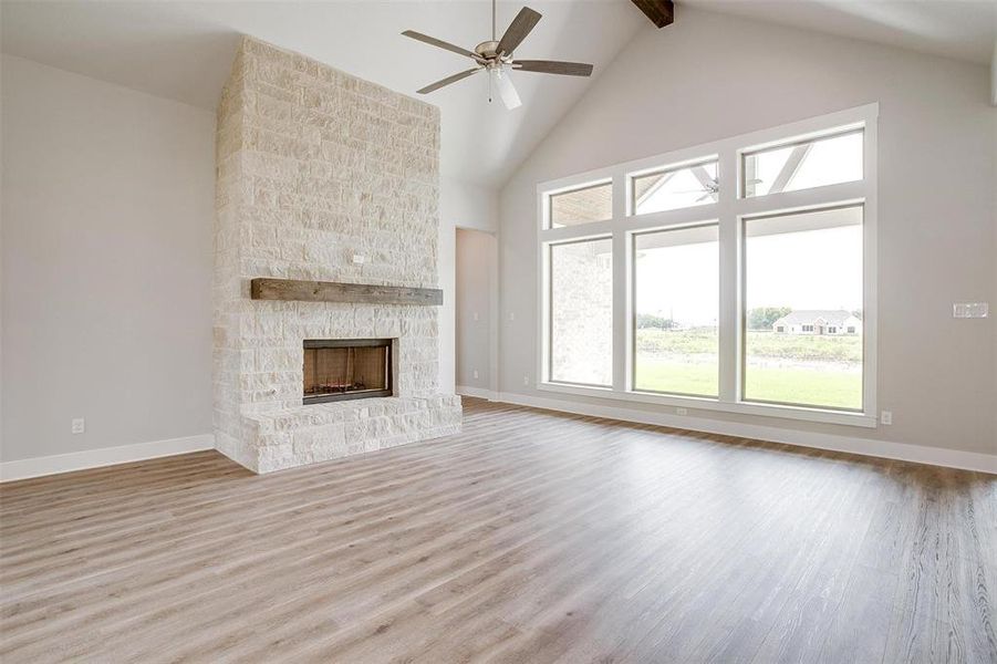 Unfurnished living room with high vaulted ceiling, beamed ceiling, hardwood / wood-style flooring, and a fireplace