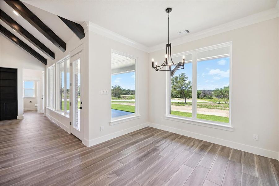 Unfurnished dining area featuring crown molding, lofted ceiling with beams, hardwood / wood-style floors, and a chandelier