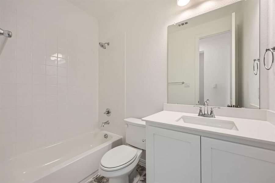 Full bathroom with vanity, tiled shower / bath combo, and toilet