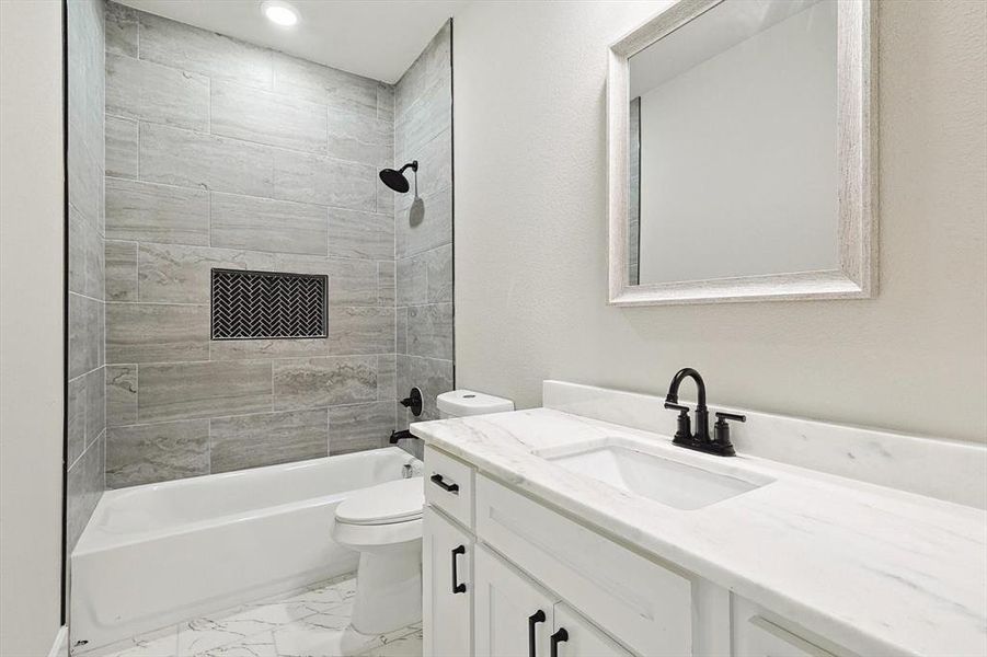 Full bathroom with tile flooring, toilet, oversized vanity, and tiled shower / bath