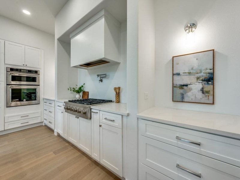 Kitchen featuring light wood-type flooring, appliances with stainless steel finishes, and white cabinets