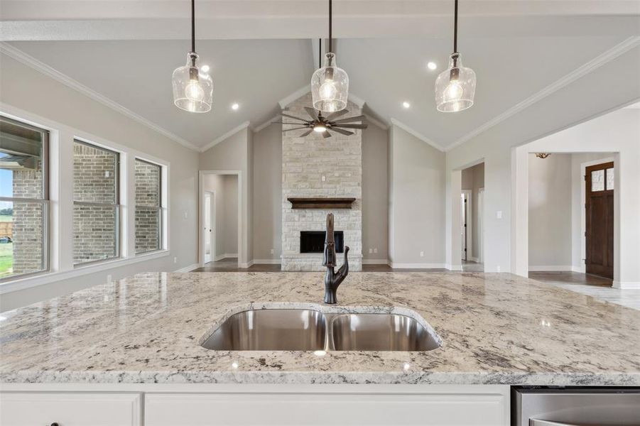 Kitchen with vaulted ceiling, a fireplace, ceiling fan, ornamental molding, and sink