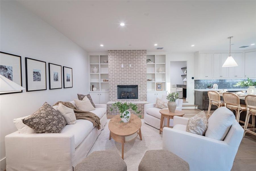 Living room with light hardwood / wood-style floors, a fireplace, and built in shelves