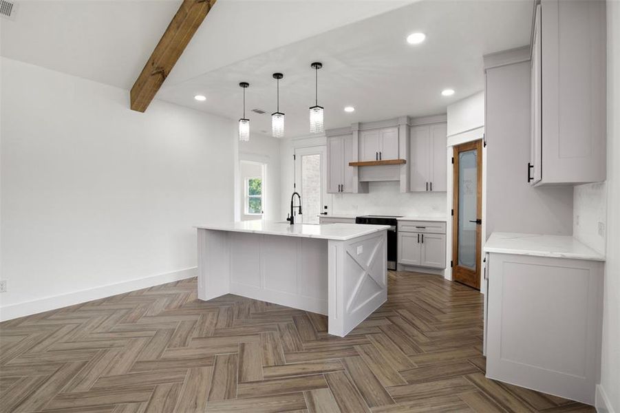 Kitchen with parquet flooring, stainless steel range, beam ceiling, a center island with sink, and hanging light fixtures