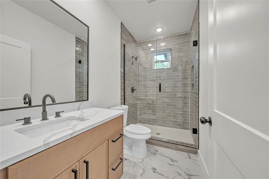 Bathroom featuring vanity, tile patterned floors, a shower with door, and toilet