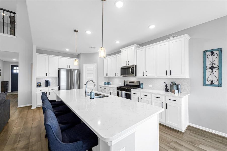 The kitchen is bright an open with lovely quartz countertops, luxurious white cabinets with under-cabinet lighting, a walk-in pantry and a gas stove!