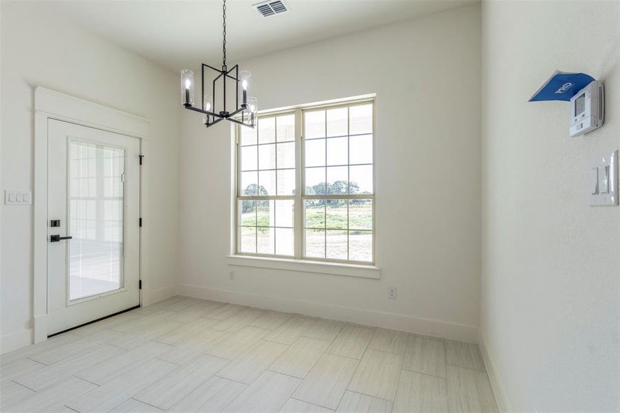 Unfurnished dining area featuring an inviting chandelier and a healthy amount of sunlight