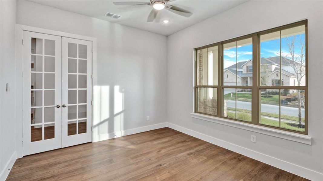 Spare room featuring french doors, ceiling fan, wood-type flooring, and a wealth of natural light