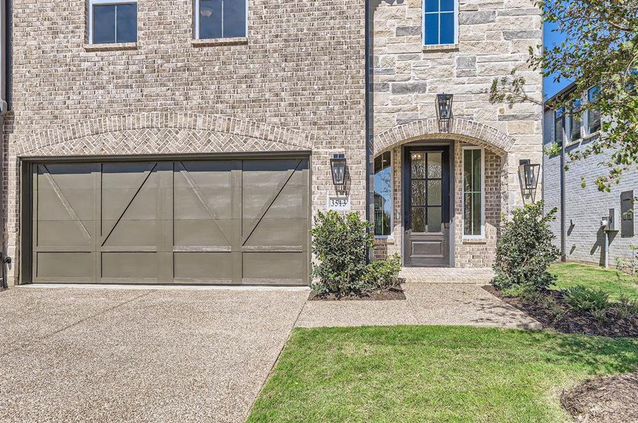 View of exterior entry with a yard and a garage