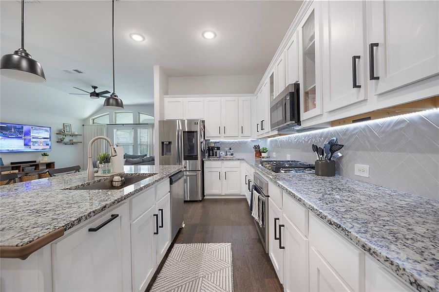 Kitchen with stainless steel appliances, pendant lighting, sink, dark hardwood / wood-style floors, and backsplash