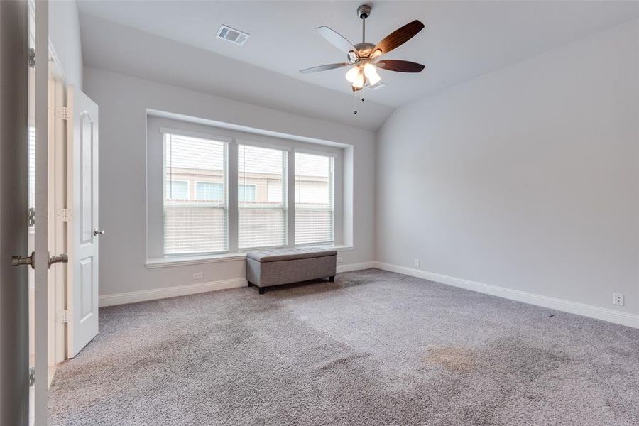 Empty room with lofted ceiling, light carpet, and ceiling fan