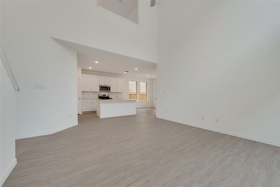 Unfurnished living room featuring a high ceiling and light wood-type flooring