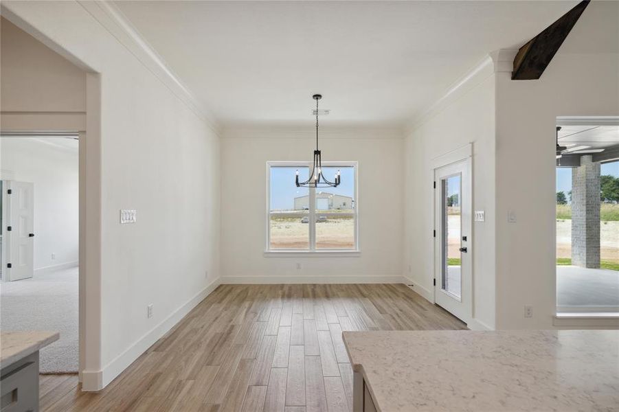 Unfurnished dining area with light hardwood / wood-style flooring, crown molding, and a chandelier