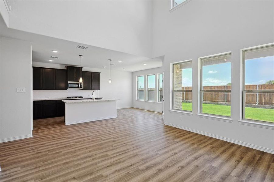 Unfurnished living room with plenty of natural light, a high ceiling, and light hardwood / wood-style flooring